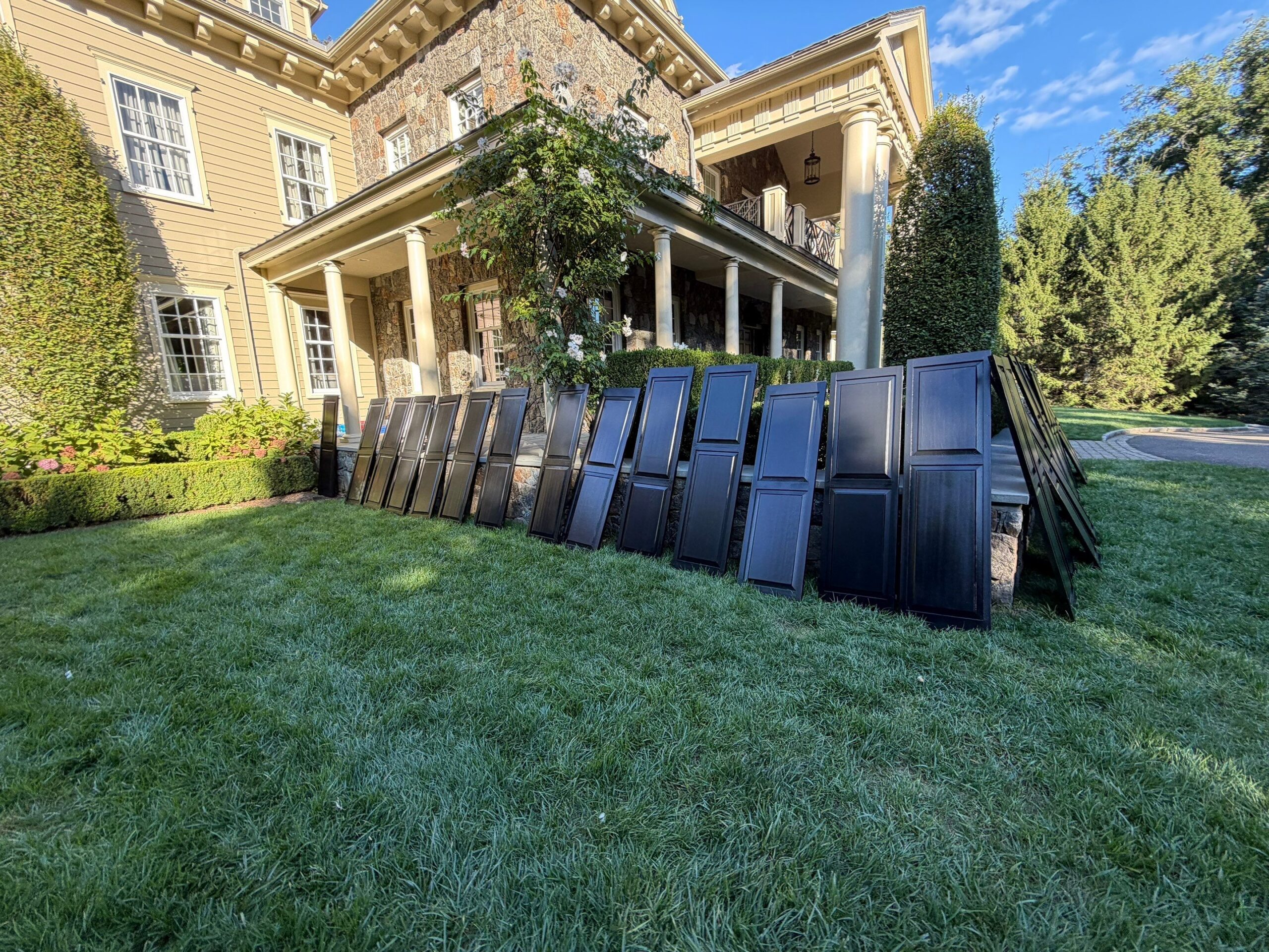 Dark window shutters on lawn prepped for painting in CT