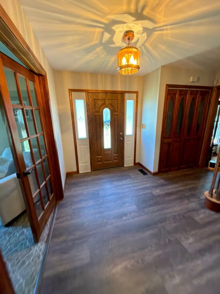 Warm entryway lighting illuminating a wooden front door and hallway walls