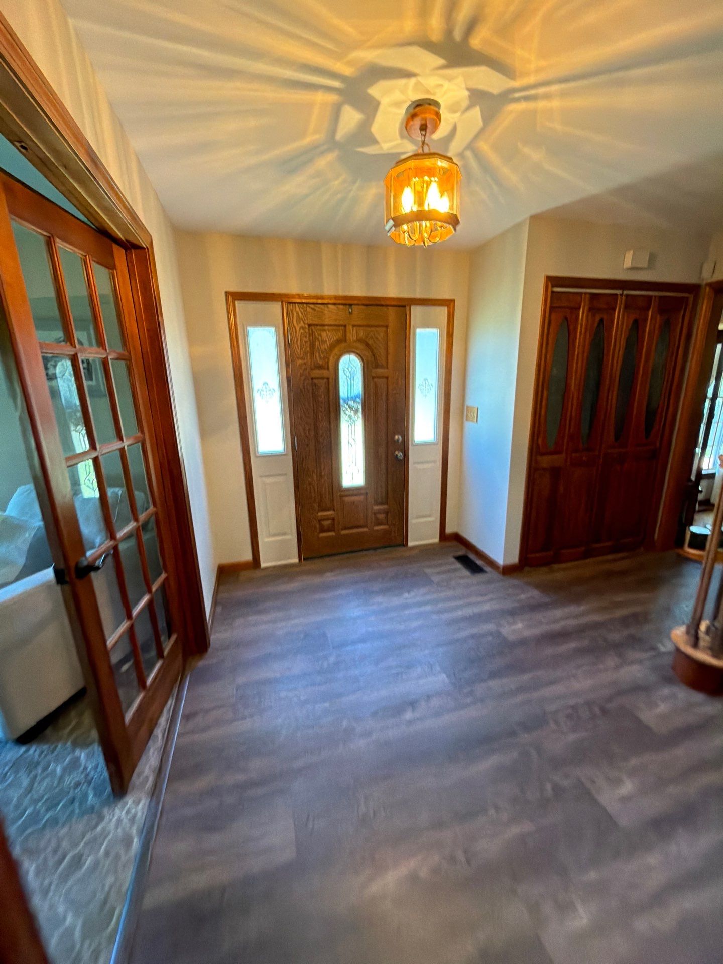 Warm entryway lighting illuminating a wooden front door and hallway walls