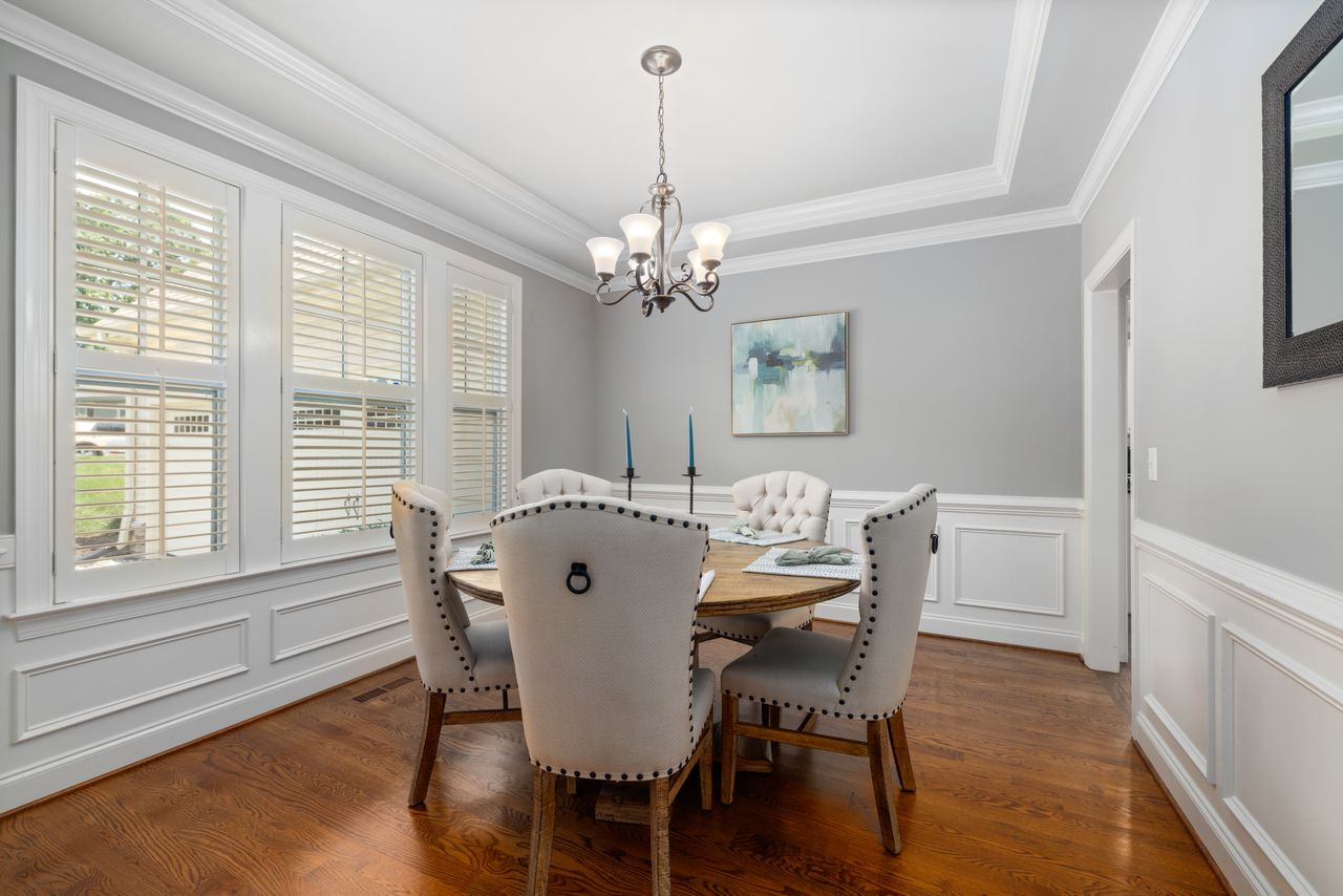 Modern dining area featuring light gray walls, chandelier, and hardwood floors