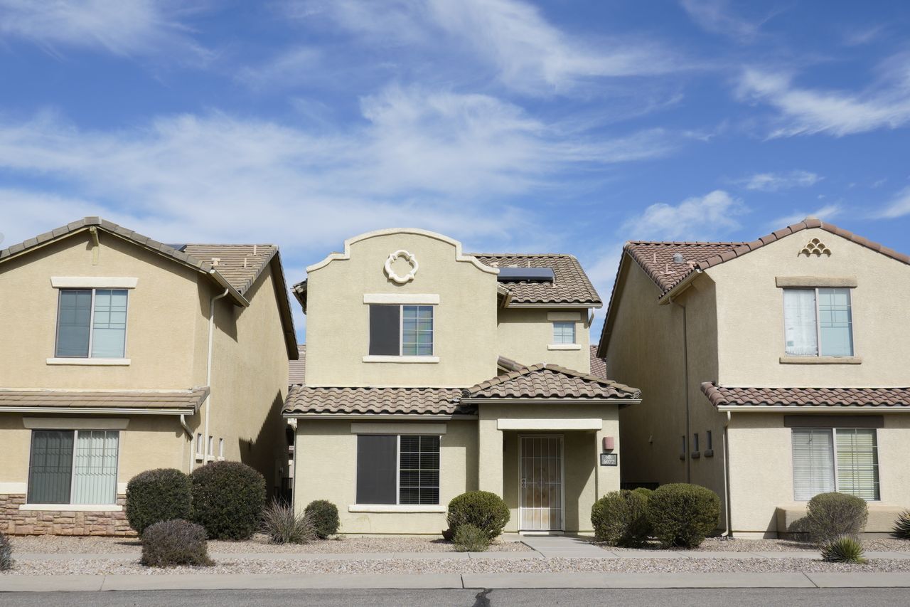 Row of two-story stucco houses with tile roofs under a blue sky
