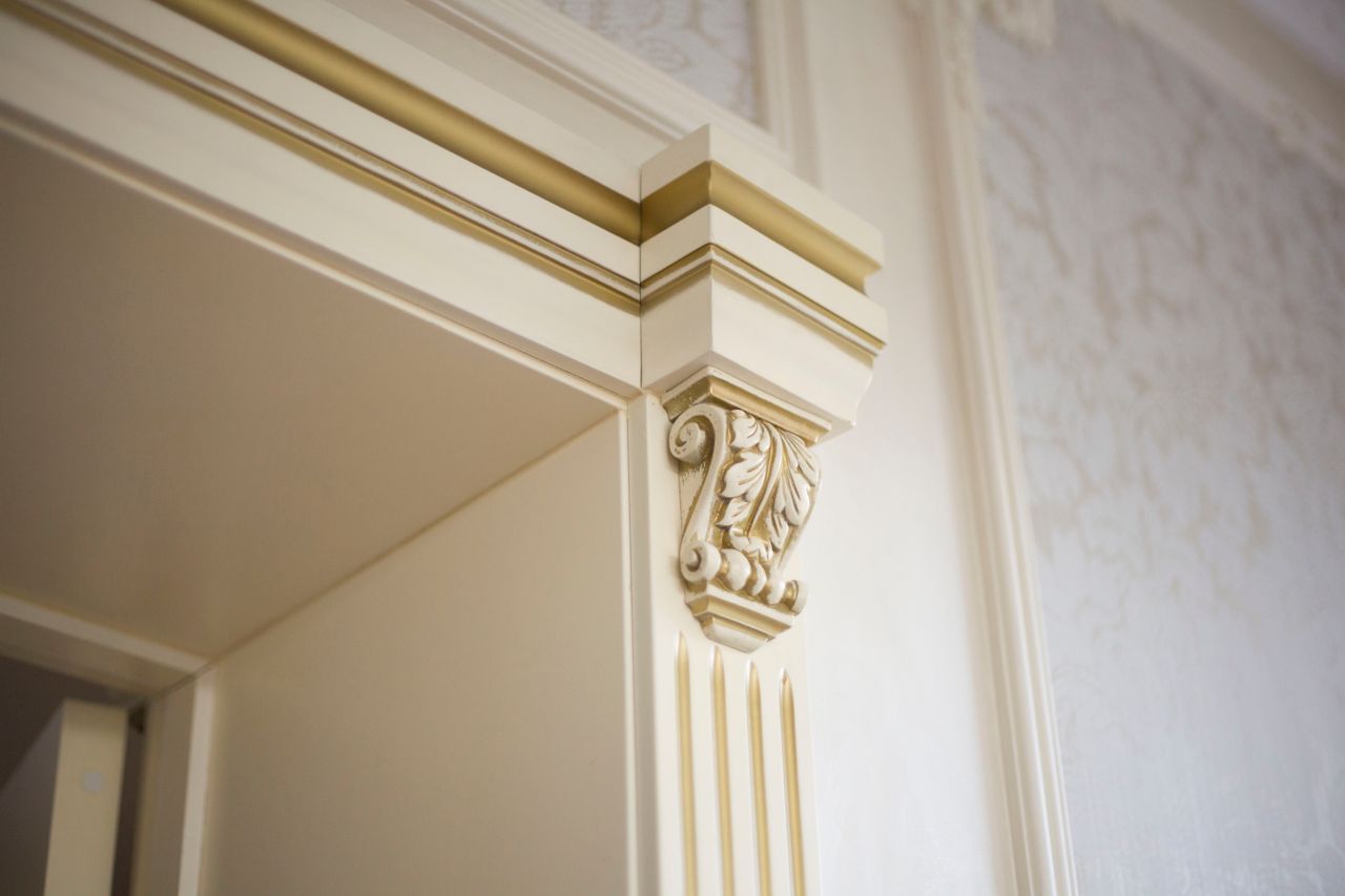 Close-up of white decorative crown molding with ornate gold accents